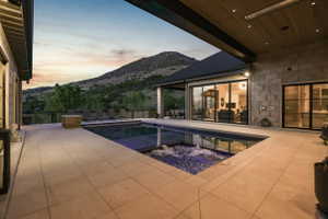 Pool at dusk with a patio, a mountain view, and a pool with connected hot tub