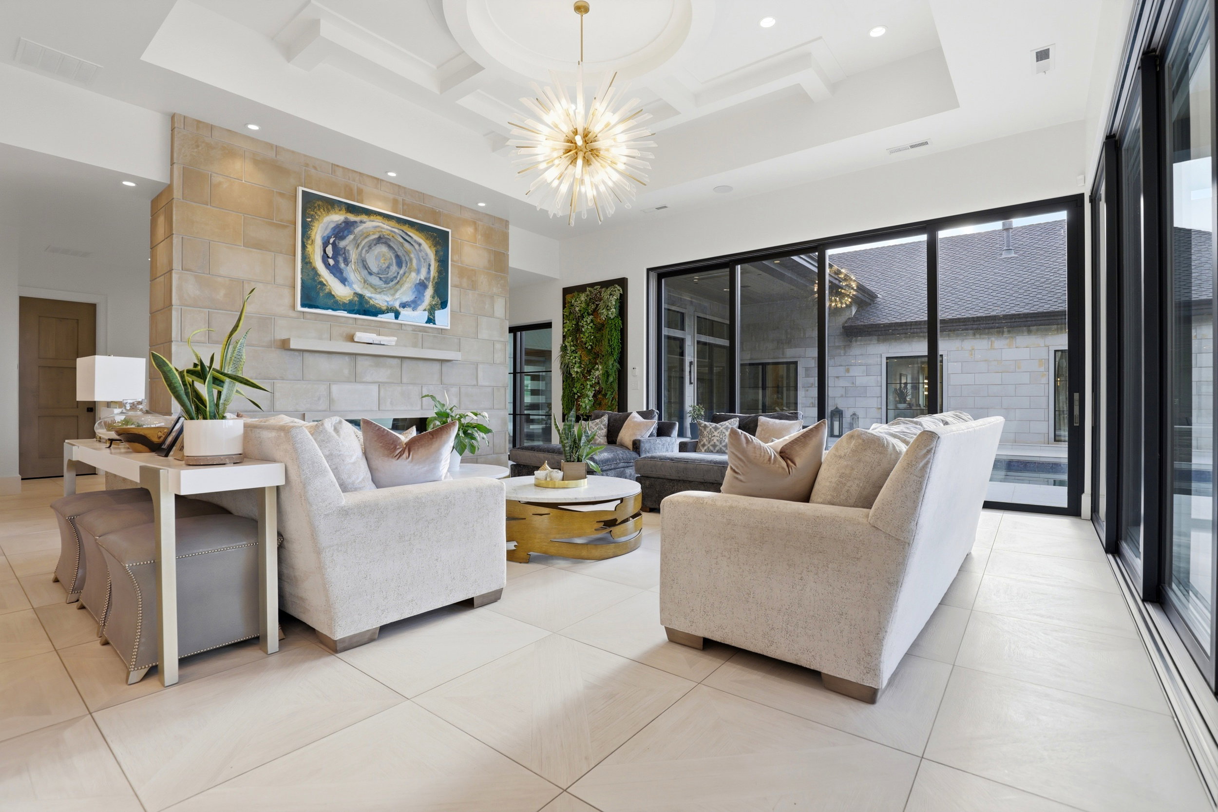 Living area featuring coffered ceiling, a fireplace, light tile patterned floors, and a chandelier