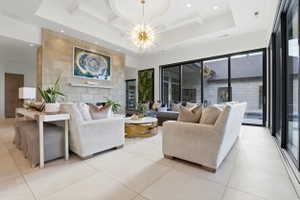 Living area featuring coffered ceiling, a fireplace, light tile patterned floors, and a chandelier