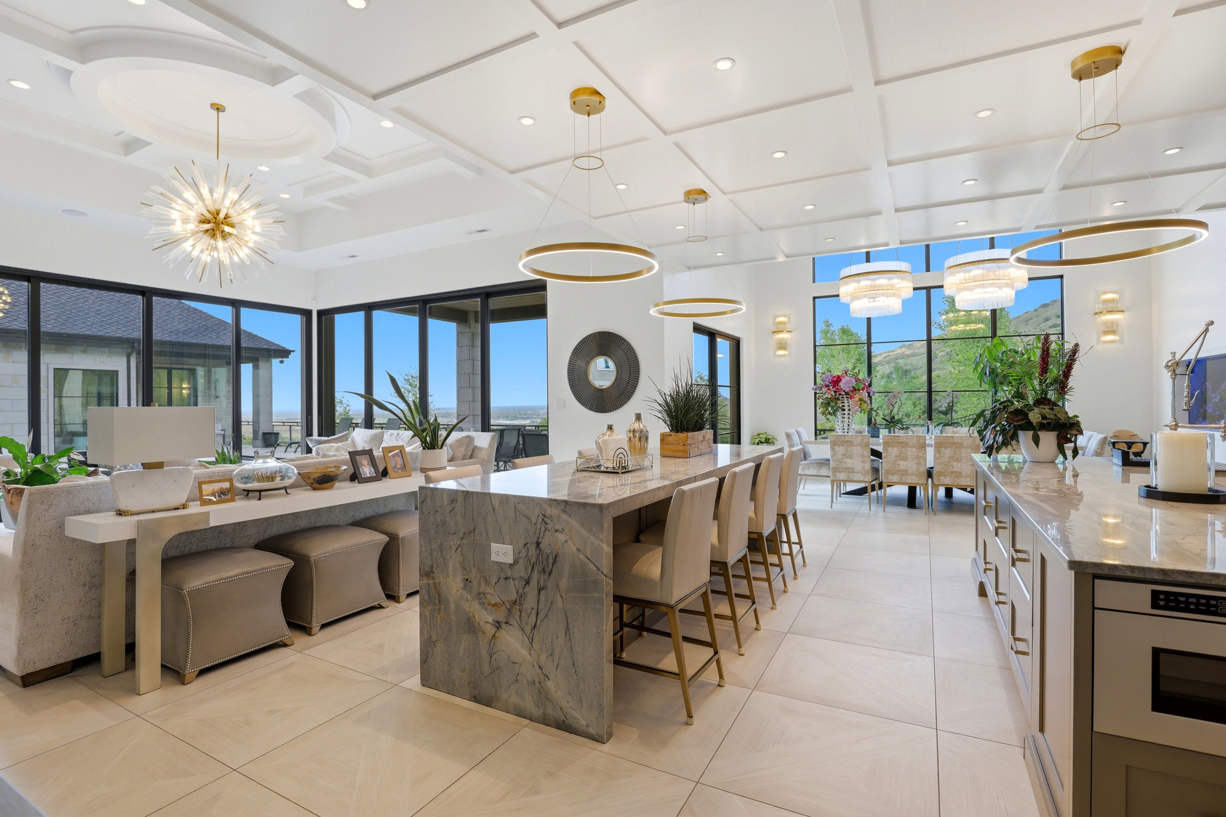 Kitchen featuring suspended lighting, coffered ceiling, light stone counters, open floor plan, and oven