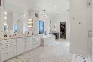 Full bath with two vanities, a walk in closet, a stall shower, a bath, and hanging lights
