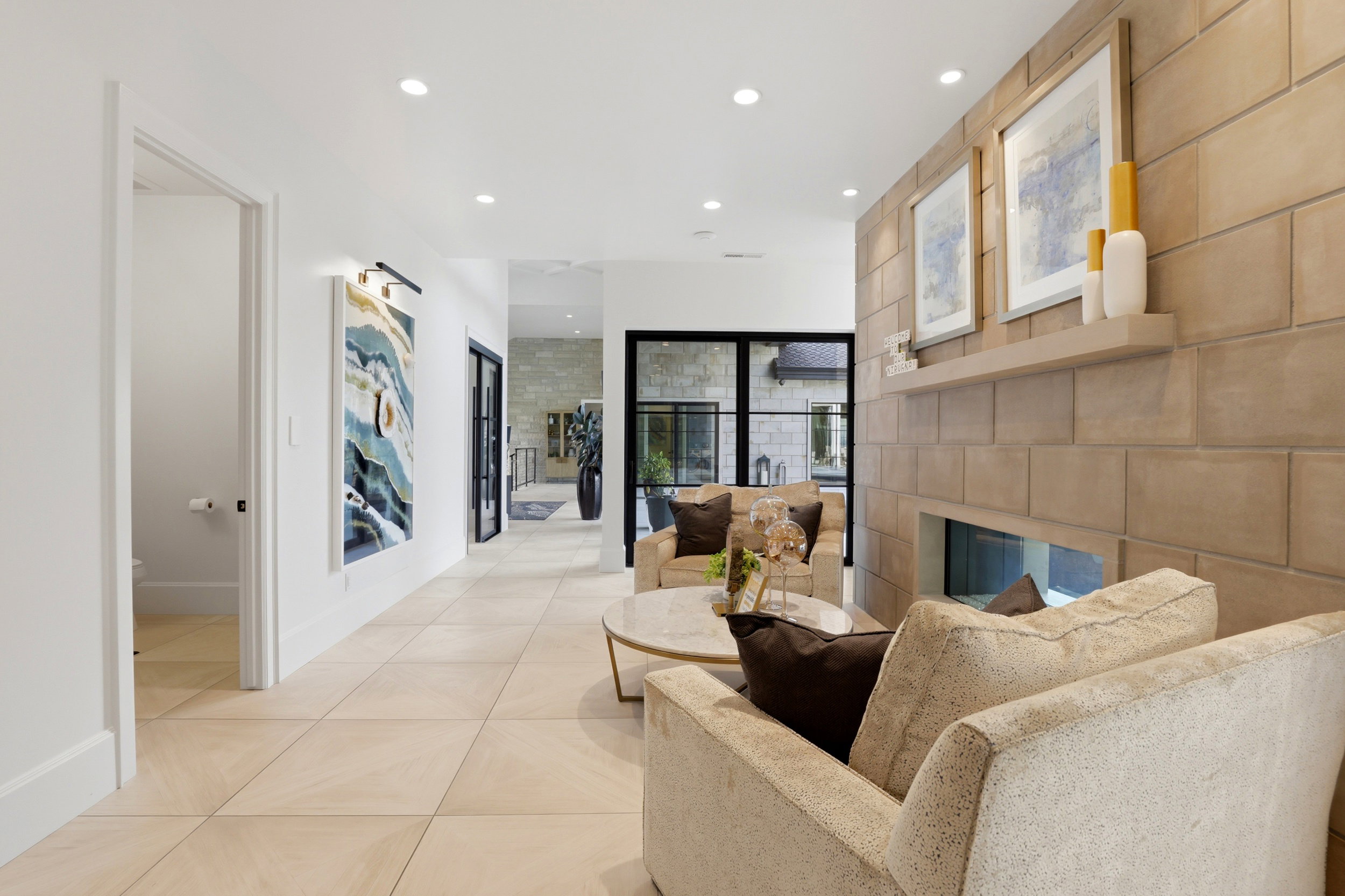Sitting room featuring a glass covered fireplace, recessed lighting, light tile patterned floors, and an accent wall
