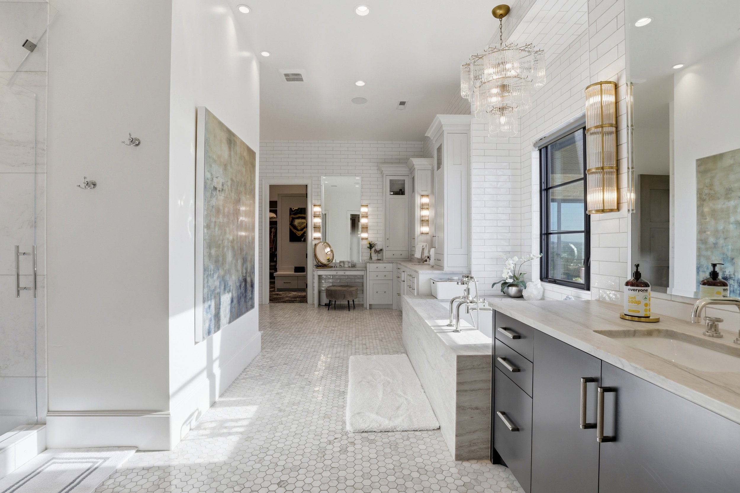 Bathroom with two vanities, a garden tub, a marble finish shower, light tile patterned flooring, and a chandelier