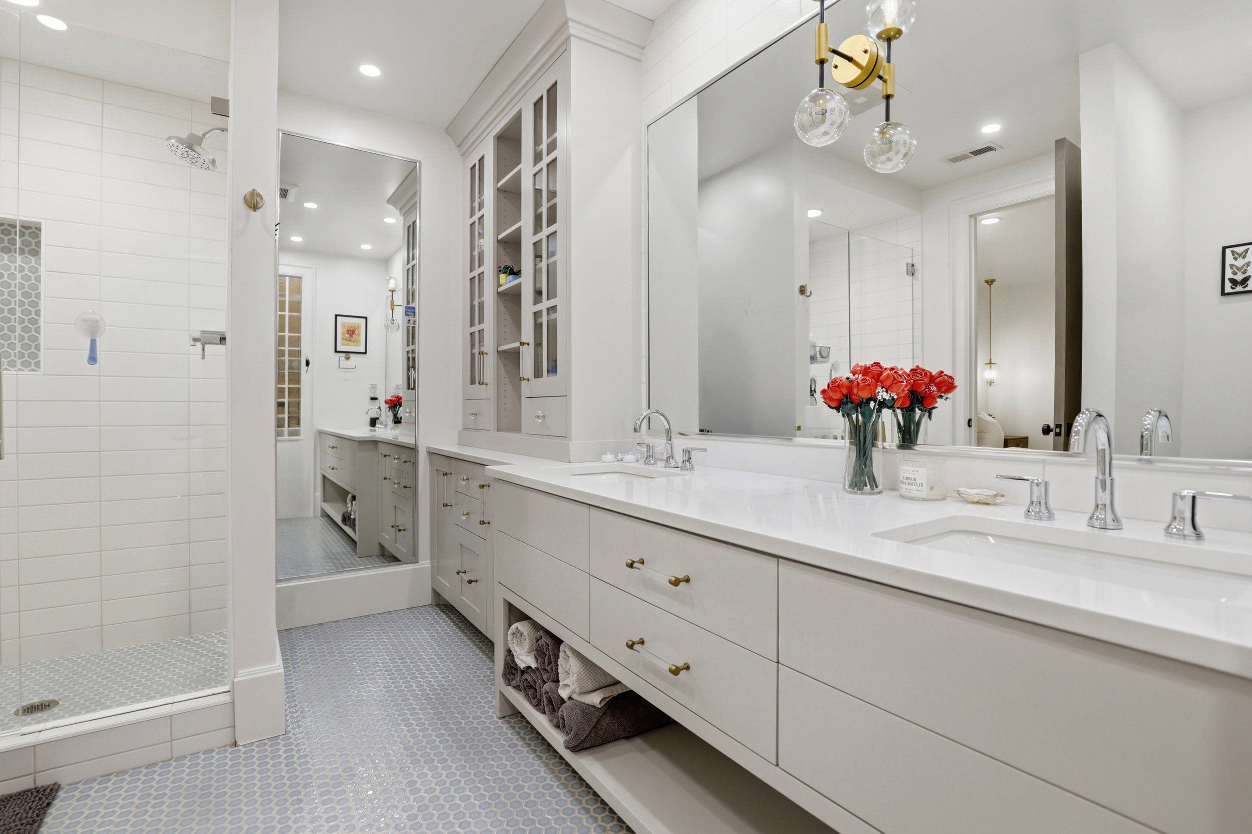 Bathroom with double vanity, a shower stall, light tile patterned floors, and recessed lighting