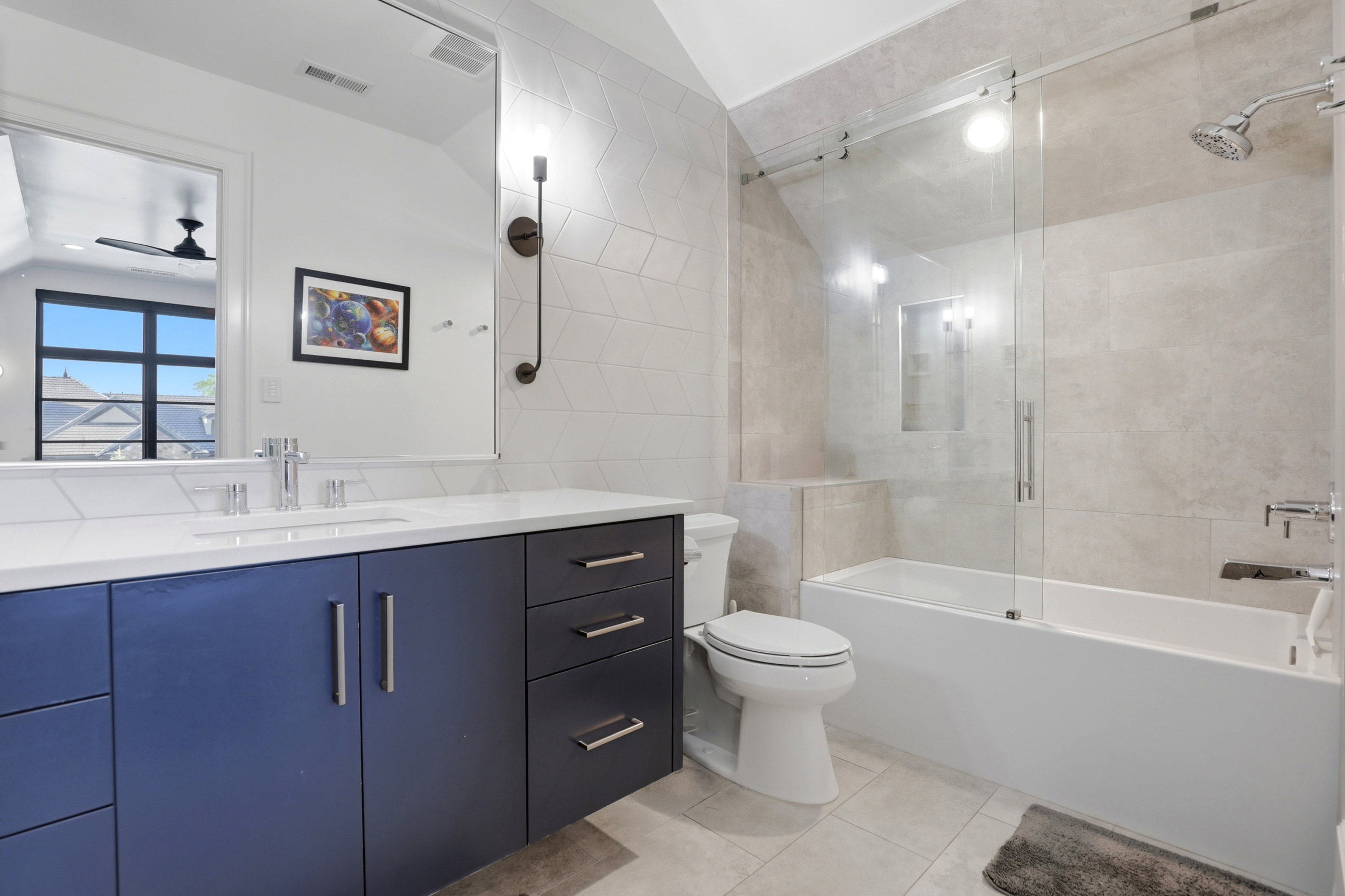 Full bath featuring vanity, tile walls, combined bath / shower with glass door, vaulted ceiling, and light tile patterned floors