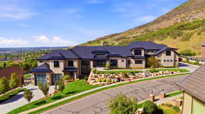 Modern inspired farmhouse featuring a garage, a mountain view, a standing seam roof, stone siding, and concrete driveway