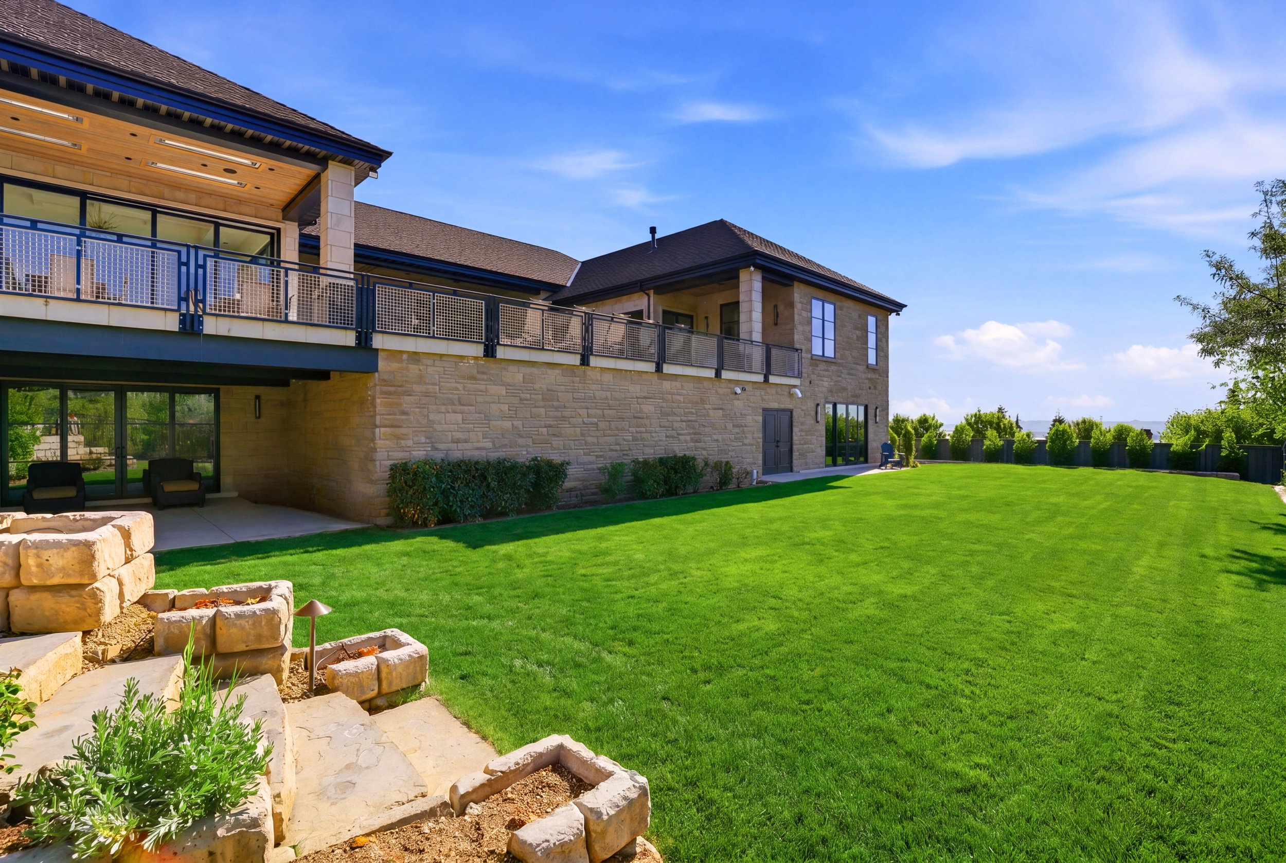 View of green lawn with a balcony and a patio