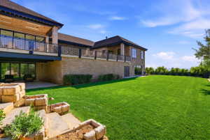 View of green lawn with a balcony and a patio