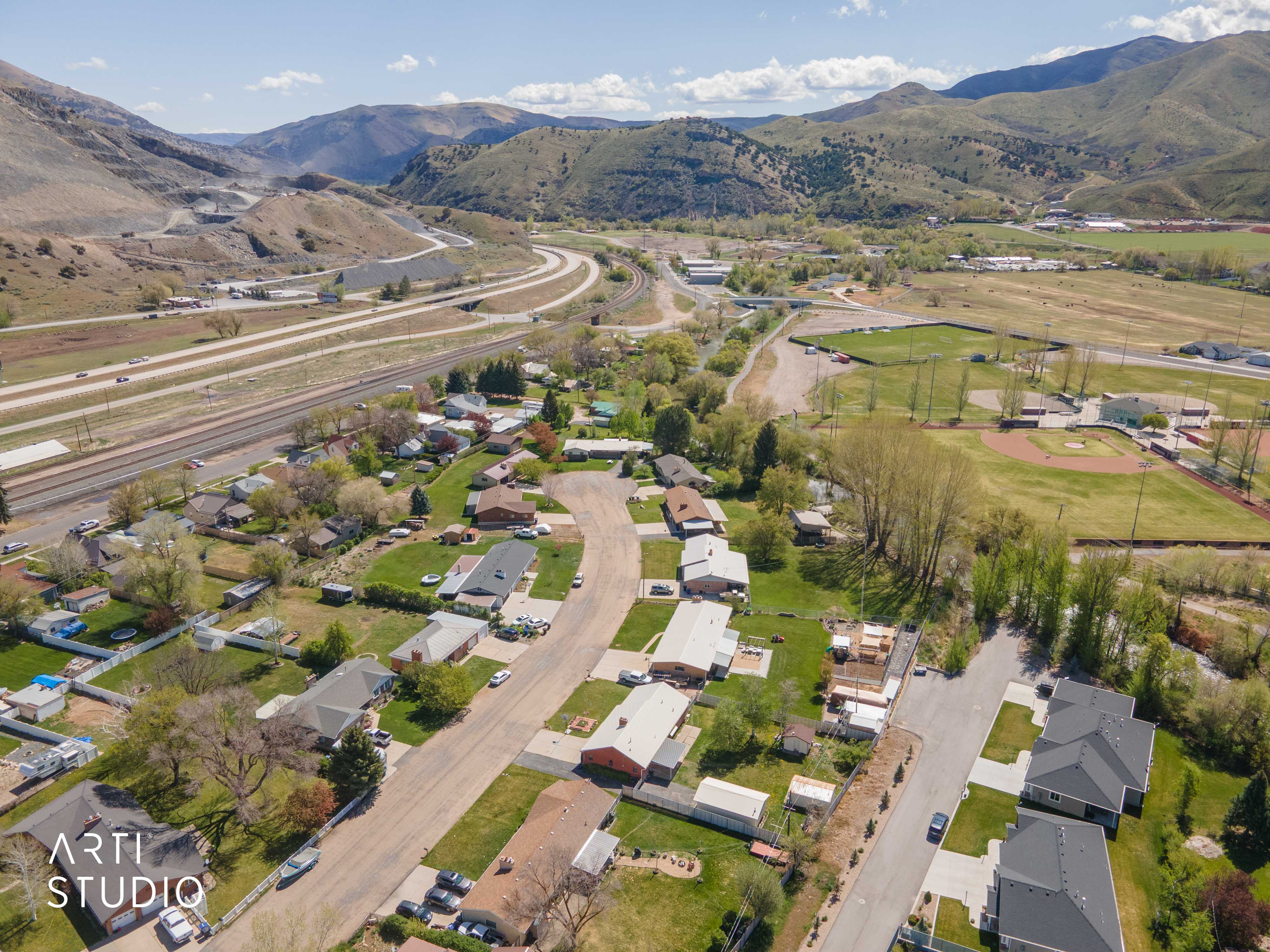Aerial view of property and surrounding area featuring nearby suburban area and a mountain backdrop