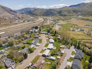 Aerial view of property and surrounding area featuring nearby suburban area and a mountain backdrop