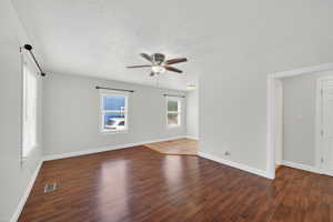 Unfurnished room with dark wood finished floors, a ceiling fan, and a textured ceiling