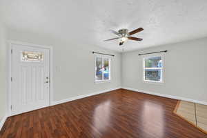Foyer with dark wood finished floors, ceiling fan, and a textured ceiling