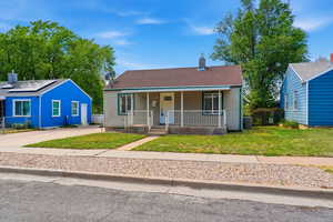 Bungalow featuring covered porch, a front lawn, a chimney, and a shingled roof