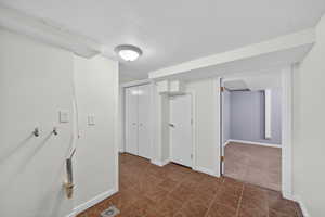 Hallway featuring a textured ceiling and baseboards