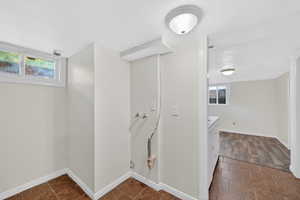 Laundry area with a textured ceiling, healthy amount of natural light, washer hookup, and stone tile flooring