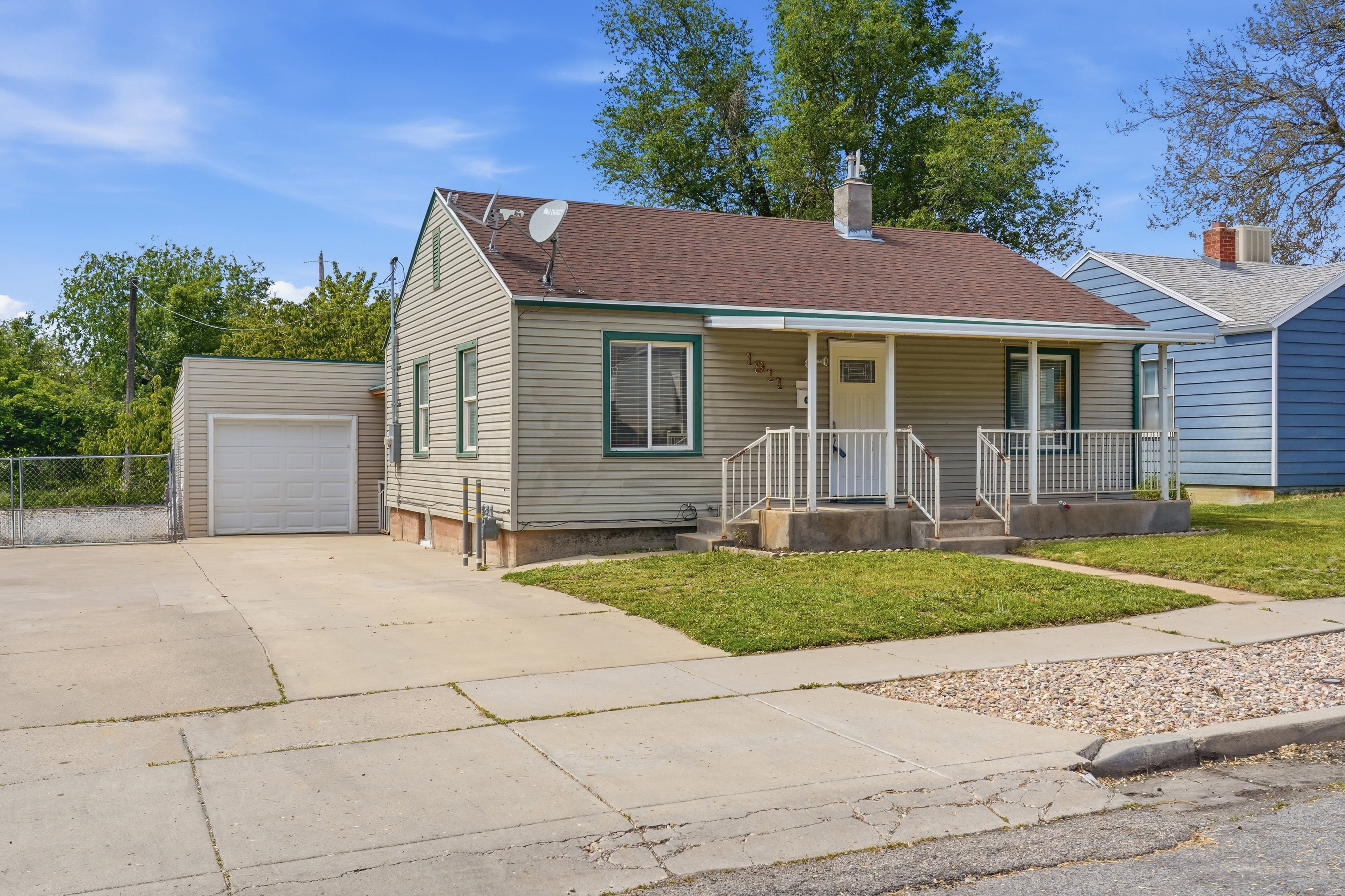 View of front of property featuring a porch, driveway, a garage, a chimney, and roof with shingles