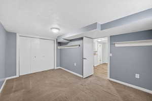 Unfurnished bedroom featuring carpet floors, a textured ceiling, and a closet