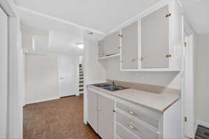 Kitchen with light countertops, a textured ceiling, and white cabinetry
