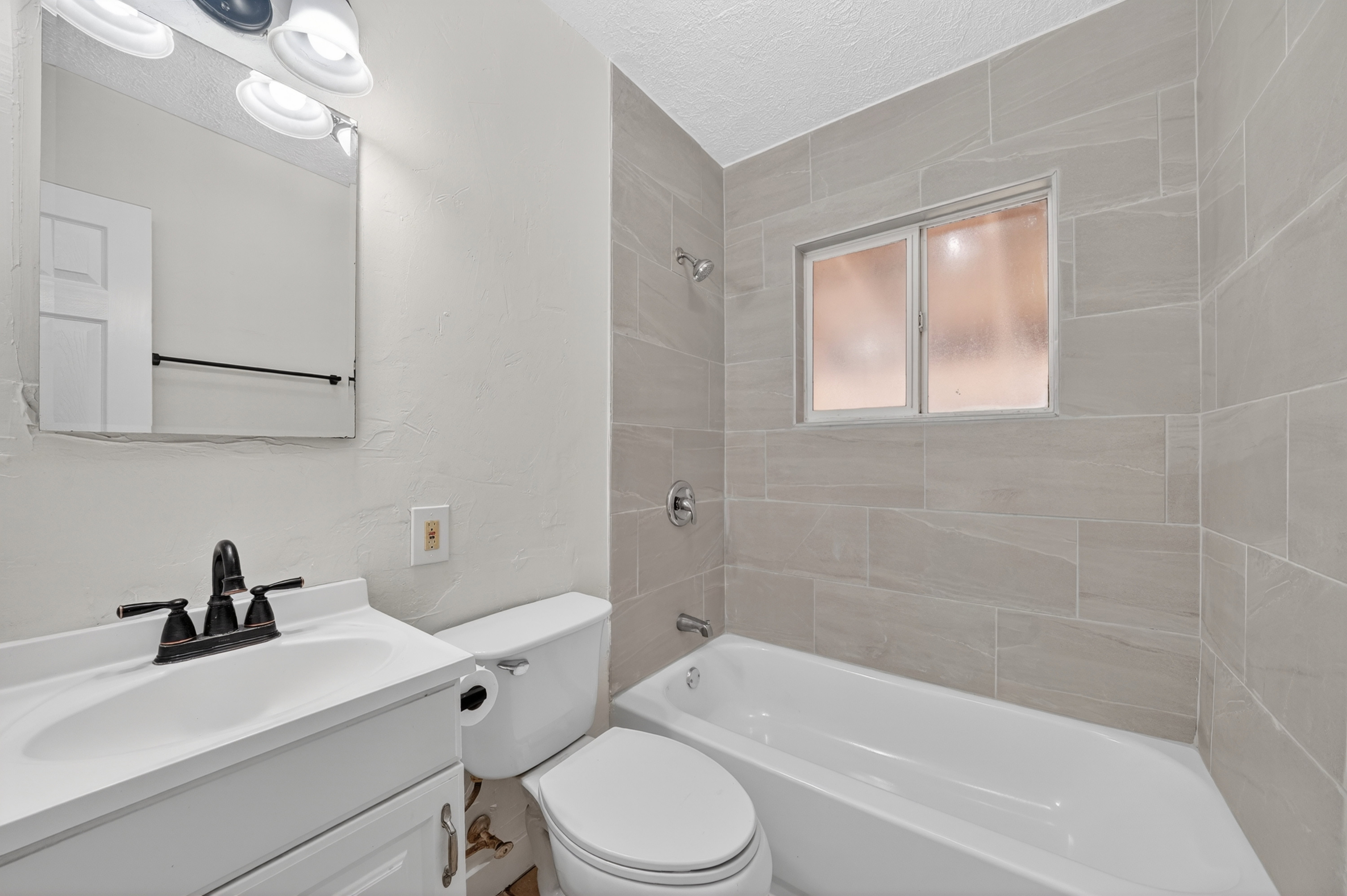 Full bath featuring vanity, a textured ceiling, bathing tub / shower combination, and a textured wall