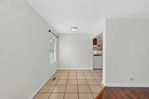 Spare room with healthy amount of natural light, washer / clothes dryer, and light tile patterned floors