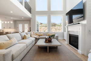 Living area featuring light wood-style flooring, recessed lighting, a tile fireplace, french doors, and a high ceiling