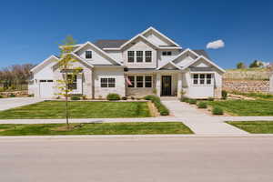 Craftsman inspired home with stone siding, board and batten siding, a front lawn, driveway, and a shingled roof