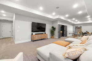 Living area with light carpet, recessed lighting, and a raised ceiling