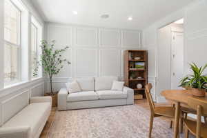 Living room with a decorative wall, wood finished floors, and recessed lighting