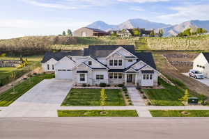 Modern farmhouse featuring stone siding, driveway, a mountain view, a garage, and roof with shingles