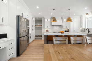 Kitchen with white cabinets, a kitchen bar, freestanding refrigerator, light wood-style floors, and backsplash