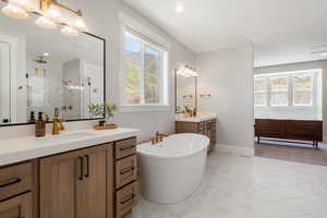 Full bath featuring two vanities, light marble finish floors, plenty of natural light, a marble finish shower, and recessed lighting