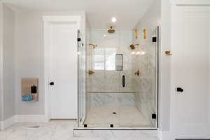 Bathroom featuring a marble finish shower, light marble finish floors, and recessed lighting
