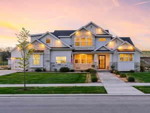 Craftsman inspired home with stone siding, board and batten siding, a yard, driveway, and a garage