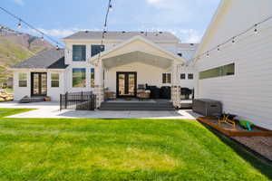 Rear view of property with french doors, a lawn, and a patio