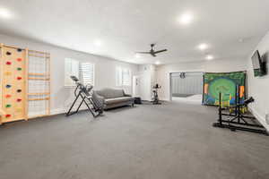 Exercise room featuring a ceiling fan, a textured ceiling, and recessed lighting
