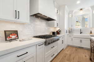 Kitchen with white cabinetry, light wood finished floors, stainless steel gas cooktop, recessed lighting, and tasteful backsplash