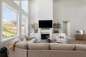 Living room with a high ceiling, wood finished floors, and a fireplace