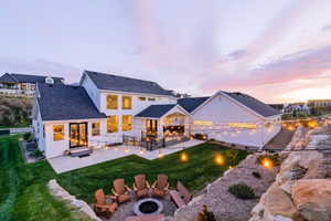 Rear view of property featuring an outdoor fire pit, roof with shingles, board and batten siding, a patio area, and a lawn