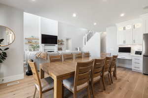 Dining area with light wood-style flooring, recessed lighting, built in desk, and a fireplace
