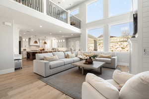 Living area featuring light wood-type flooring, recessed lighting, healthy amount of natural light, and a high ceiling