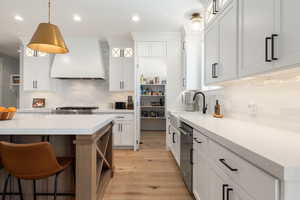 Dual tone kitchen featuring a kitchen bar, light wood-style floors, open shelves, light stone counters, and two tone cabinets