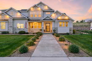 Craftsman-style house featuring board and batten siding, stone siding, a front lawn, and a porch