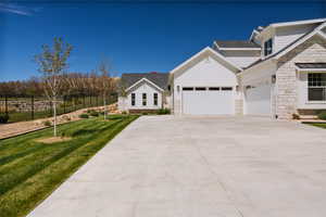 View of front facade with stone siding, concrete driveway, an attached garage, and a shingled roof