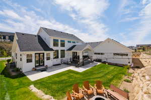 Rear view of house featuring a shingled roof, a patio area, board and batten siding, and entry steps