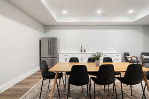 Dining room with a raised ceiling, recessed lighting, and light wood-style floors