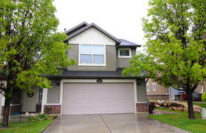 View of front facade featuring brick siding, driveway, a garage, and board and batten siding