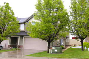 View of front of house featuring brick siding, a 2-car garage, stucco siding, concrete driveway, and a shingled roof