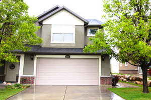 View of front of house featuring brick siding, a 2-car garage, stucco siding, concrete driveway, and a shingled roof