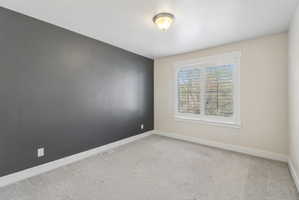 Spare room with baseboards and light colored carpet