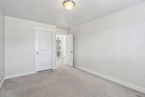 Unfurnished bedroom with light carpet and baseboards